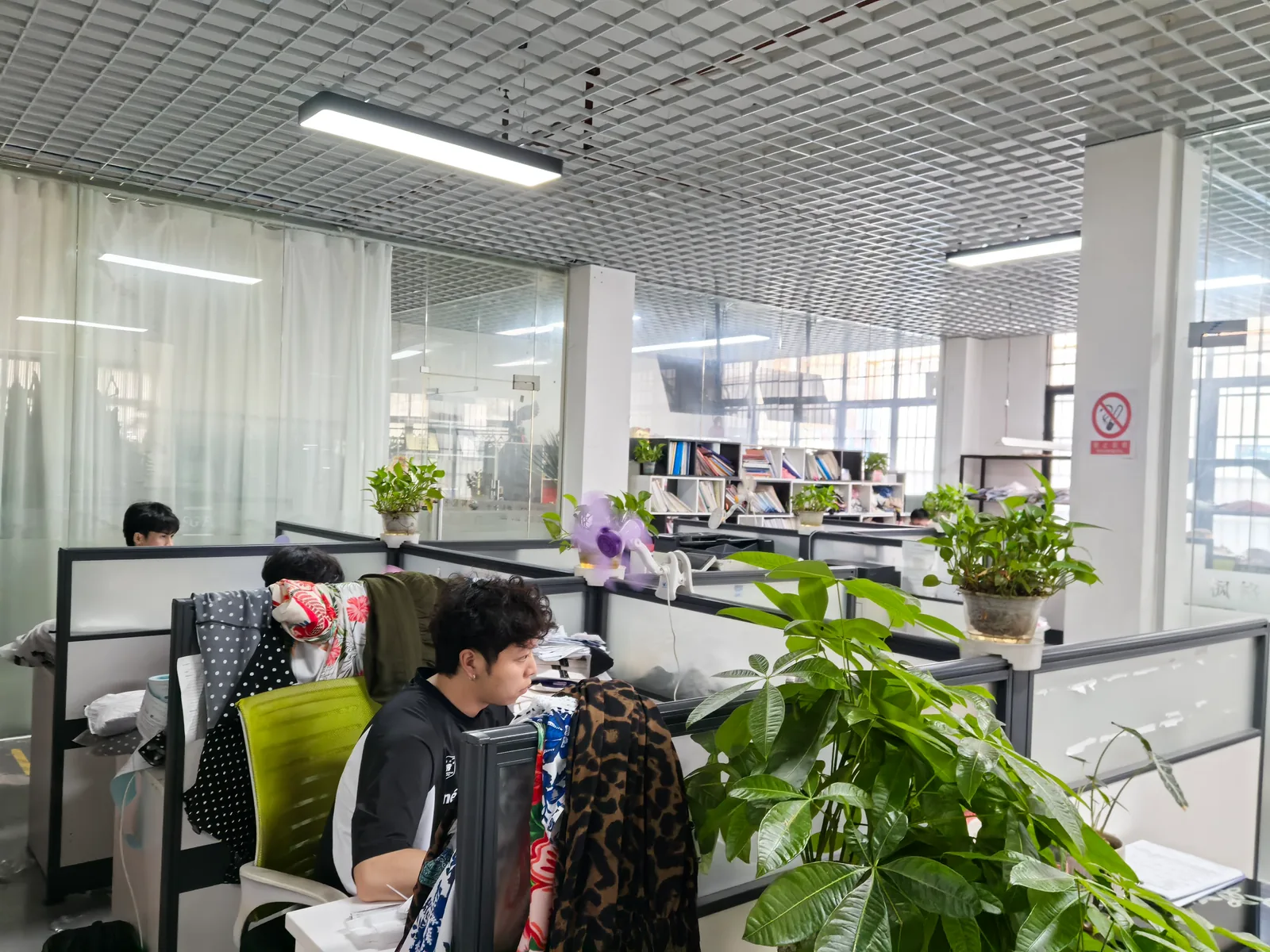 Bright apparel factory office with staff supporting OEM clothing orders and production planning